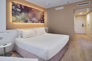 塔拉薩的住宿－Eurostars Don Cándido，卧室配有白色的床和墙上的绘画作品