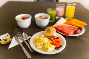 a table with two plates of breakfast food and drinks at Hotel Golden Star in Curitiba
