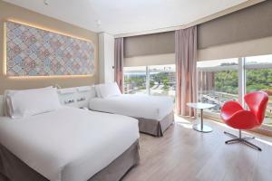 a hotel room with two beds and a red chair at Eurostars Don Cándido in Terrassa +29 photos