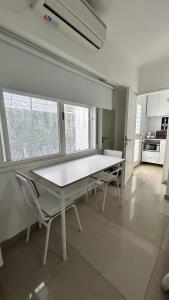uma mesa branca e cadeiras numa cozinha em Hermoso y cómodo alojamiento con patio en Nuñez em Buenos Aires