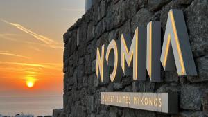Tagou的住宿－Nomia Sunset Suites Mykonos，墙上的现在标志,有日落