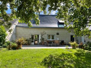 a white house with a patio and a yard at Chambres d hôtes avec Piscine et Spa La Folière Saumur in Villebernier