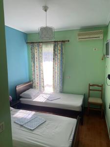 two beds in a room with a window and a chair at Sea View Apartment in Sarandë
