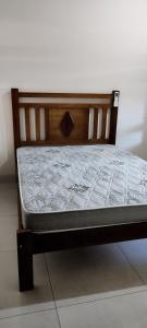 1 cama con marco de madera en el suelo en casa condomínio próximo à praia en Caraguatatuba