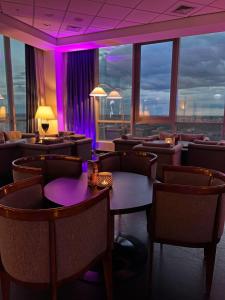 un restaurant avec des tables, des chaises et un éclairage violet dans l'établissement Radisson Blu Szczecin, à Szczecin