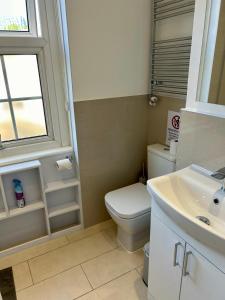 baño con aseo y lavabo y ventana en Kings Cross Guest House, en Londres