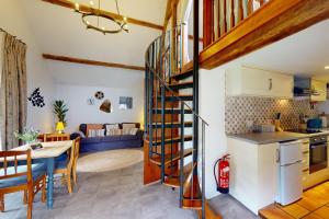 una cocina y una sala de estar con una escalera de caracol en una casa en Smiddy Cottage Hawkridge, en Dulverton