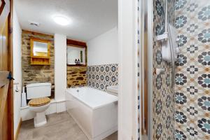 a bathroom with a toilet and a tub and a sink at Smiddy Cottage Hawkridge in Dulverton +32 photos