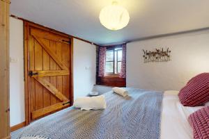 a bedroom with a large bed with a wooden door at Smiddy Cottage Hawkridge in Dulverton