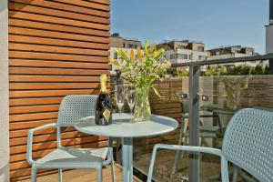 een tafel met een fles wijn en bloemen op een balkon bij Aparthotel Anchoria BlueApart in Mechelinki