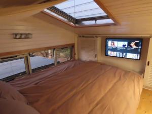 ein Bett in einem winzigen Haus mit einem Fernseher in der Unterkunft BellaTiny, Tiny House & Gypsy Wagon in Ondekaremba