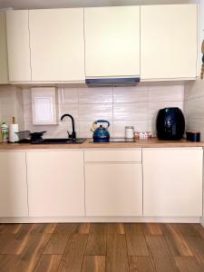 kuchnia z białymi szafkami i drewnianą podłogą w obiekcie Apartament Centrum w Łańcucie +3 zdjęcia