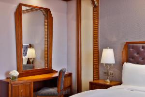 The Ritz-Carlton Jeddah في جدة: غرفة نوم مع مرآة وسرير وكرسي