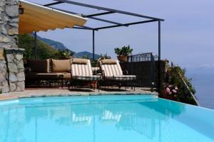 a patio with chairs and a swimming pool at De Vivo Realty - Villa Stone Positano in Positano