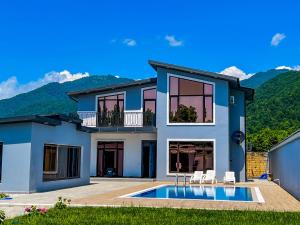 a house with a swimming pool and mountains in the background at Qafqaz Modern Harmony in Gabala