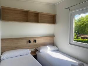 two beds in a small room with a window at Resort Camping Santillana del Mar in Santillana del Mar