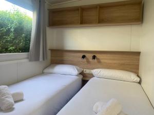 2 camas en una habitación pequeña con ventana en Resort Camping Santillana del Mar, en Santillana del Mar