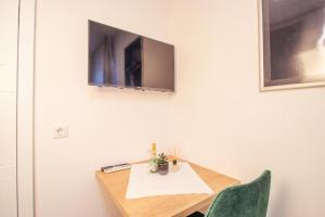 uma mesa com televisão numa parede branca em Hotel Dona em Bergisch Gladbach