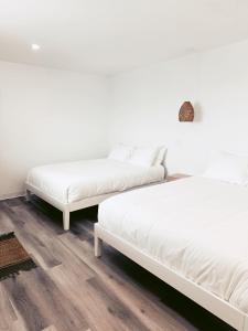 two beds in a room with white walls and wooden floors at À Bon Port in Perce