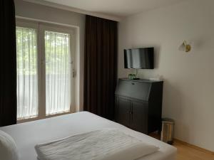 a bedroom with a bed and a tv and a window at Hotel Berg in Seekirchen am Wallersee