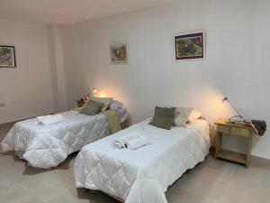 1 dormitorio con 2 camas con sábanas blancas en GMP suites en San Miguel de Tucumán