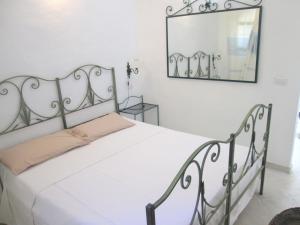 a white bed in a room with a mirror at Sardinia Yellow House in Solanas