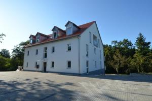 ein großes weißes Gebäude mit rotem Dach in der Unterkunft Julo Apartments Tuchenbach in Tuchenbach