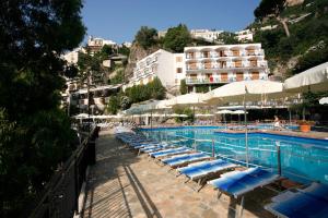 een zwembad met blauwe ligstoelen en een hotel bij Apartment Hotel Royal con balcone e vista mare in Positano