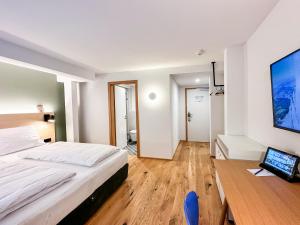 Schlafzimmer mit einem Bett, einem Schreibtisch und einem TV in der Unterkunft Hotel Wilma in Frickenhausen