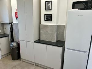 a kitchen with white cabinets and a refrigerator at Kings Cross Guest House in London