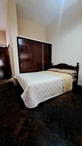 een slaapkamer met een groot bed met een houten hoofdeinde bij Hosteria Tumbaya in Tumbaya