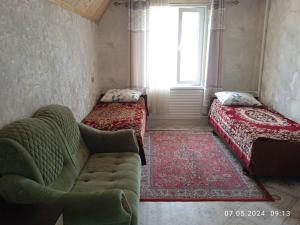 Cette chambre comprend deux lits, un canapé et une fenêtre. dans l'établissement Syimyk Guest House, à Dzhergalan