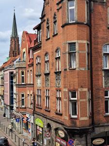 a tall brick building on a city street at Apartament w Fabryce Czekolady in Bytom