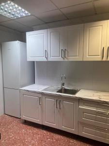 uma cozinha com armários brancos e um lavatório em just hostel capsules em Alicante