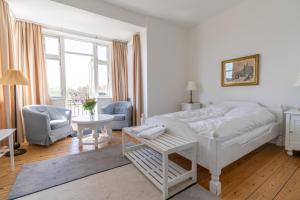 ein weißes Schlafzimmer mit einem weißen Bett und einem Stuhl in der Unterkunft Hotel Postgaarden in Skælskør