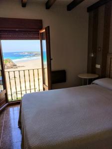 a bedroom with a bed and a view of the beach at Hostal Restaurante Parajes in Castropol