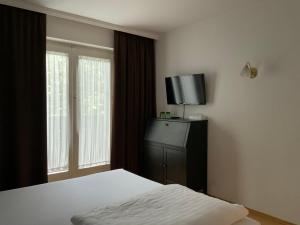 um quarto com uma cama e uma televisão de ecrã plano em Hotel Berg em Seekirchen am Wallersee