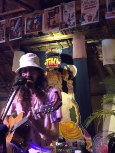 a man singing into a microphone while holding a guitar at Tiki garden in Kampot