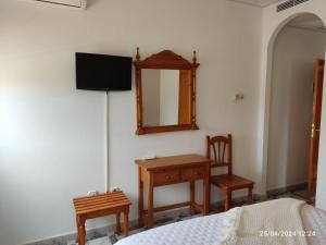 una camera con letto, scrivania e specchio di Hostal Quinto Pino a Chipiona