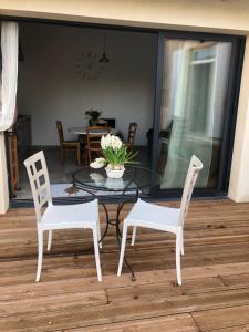 een glazen tafel met twee stoelen en een tafel met bloemen erop bij La Grange de la Brousse in La Brousse