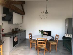 a kitchen with a table and chairs and a clock on the wall at La Grange de la Brousse in La Brousse