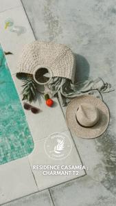 um par de chapéus e vegetais no chão ao lado de uma piscina em Résidence Casamea, charmant T2 em Talasani