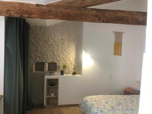 - une chambre avec un lit et un mur blanc dans l'établissement La Grange de la Brousse, à La Brousse