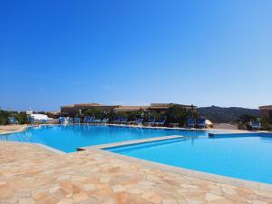 a large swimming pool with blue water and chairs at Case Vacanza Castello di Gallura in Santa Teresa Gallura