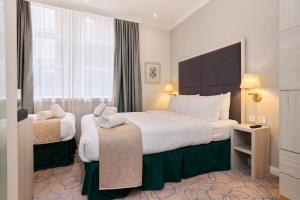 Una habitación de hotel con dos camas y una ventana. en Blandford Hotel, en Londres