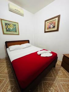a bedroom with a red and white bed with two towels at Hotel Barroco in San José