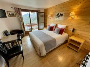 a bedroom with a bed and a table and a chair at Hôtel Chalet Le Panoramique in Mizoën