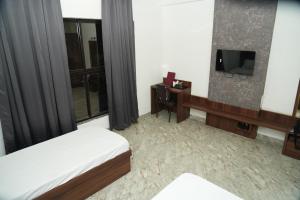 ein Hotelzimmer mit einem Bett und einem TV in der Unterkunft Madhuban Garden And Resort 