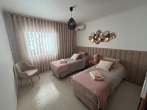 ein Hotelzimmer mit 2 Betten und einem Stuhl in der Unterkunft Rosas no Lagar in Vila Nova De Cacela