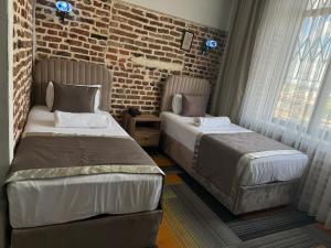 a bedroom with two beds and a brick wall at Sur Central Hotel in Diyarbakır